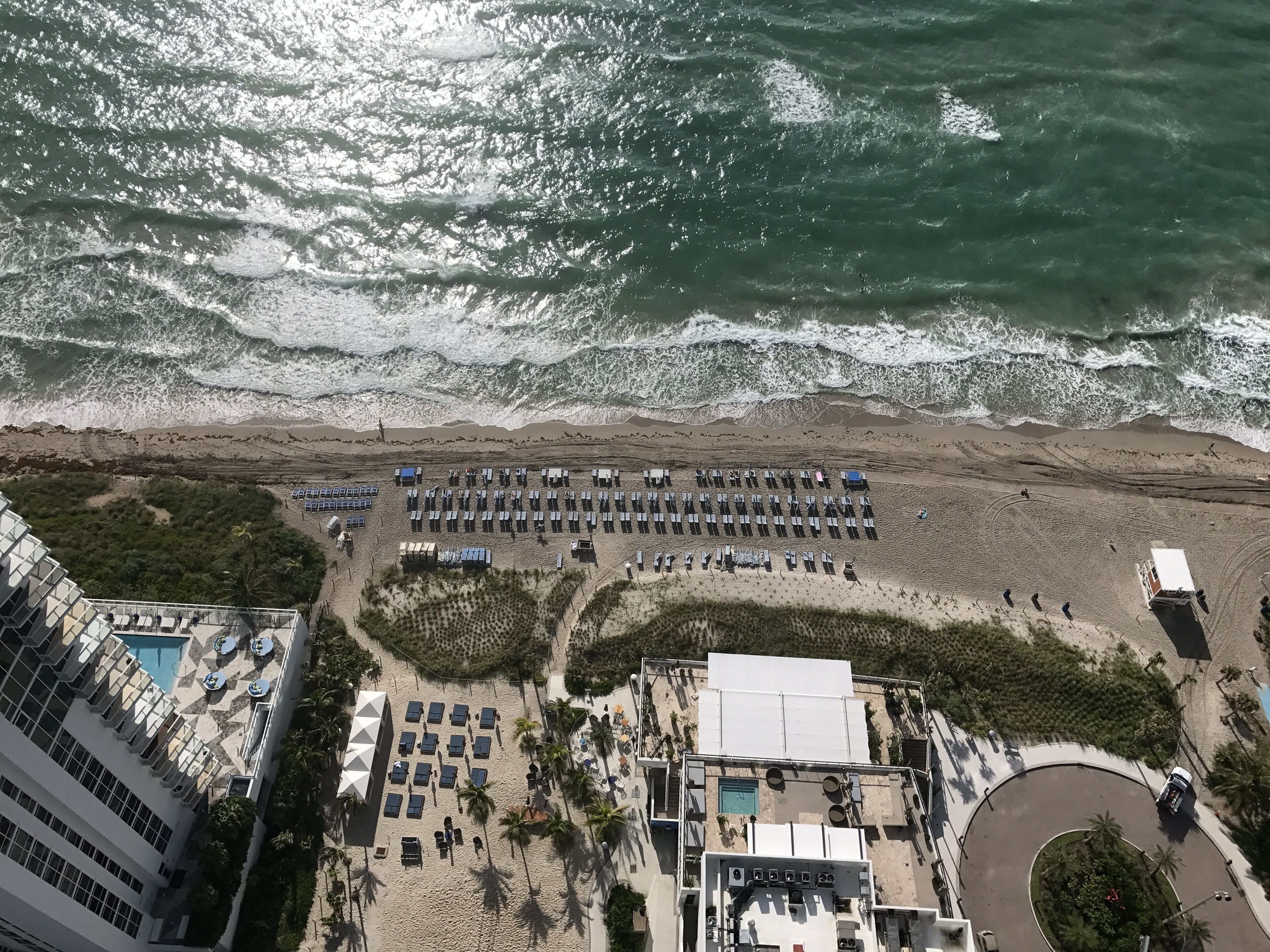 A beachfront hotel with a pool, sun loungers, and a beach area.