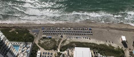 A beachfront hotel with a pool, sun loungers, and a beach area.