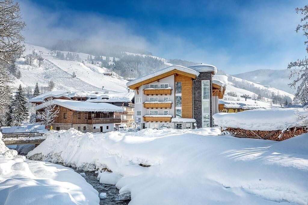 Une station de montagne enneigée, avec des bâtiments en bois et un ciel dégagé.