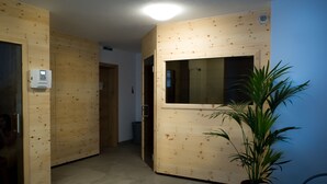 Ein Zimmer mit Holzwandverkleidung, einem Fenster, einer Pflanze und einem Stuhl.