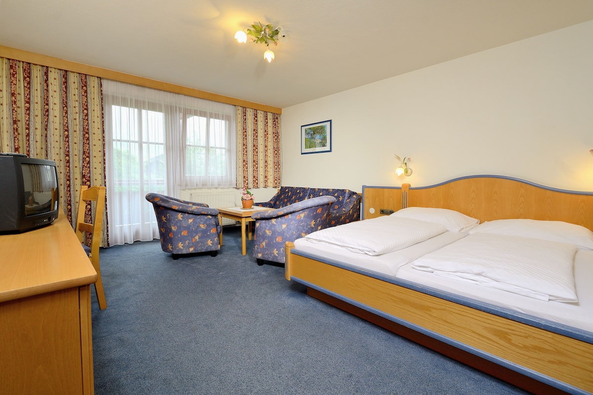Een hotelkamer met een bed, een bank, een stoel, een klein tafeltje en een televisie.