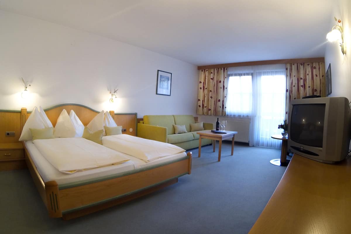 Een hotelkamer met een groot bed, een bank, een televisie en een klein tafeltje.