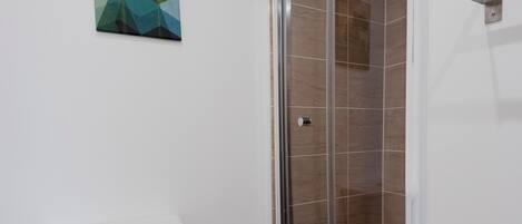 A bathroom with a toilet, a glass shower enclosure, and a wall-mounted towel rack.