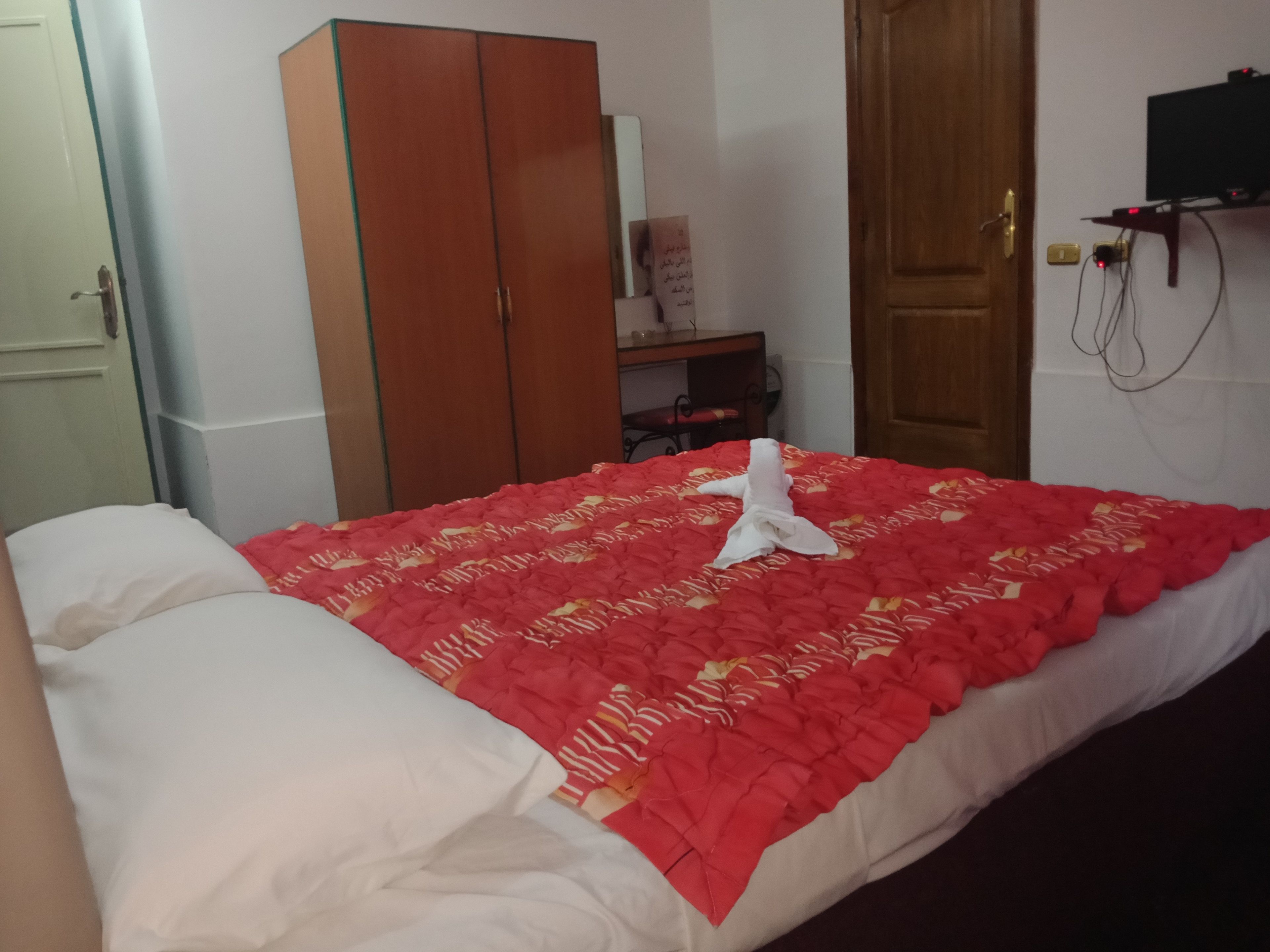 A hotel room with a bed, a wardrobe, a desk, and a television.