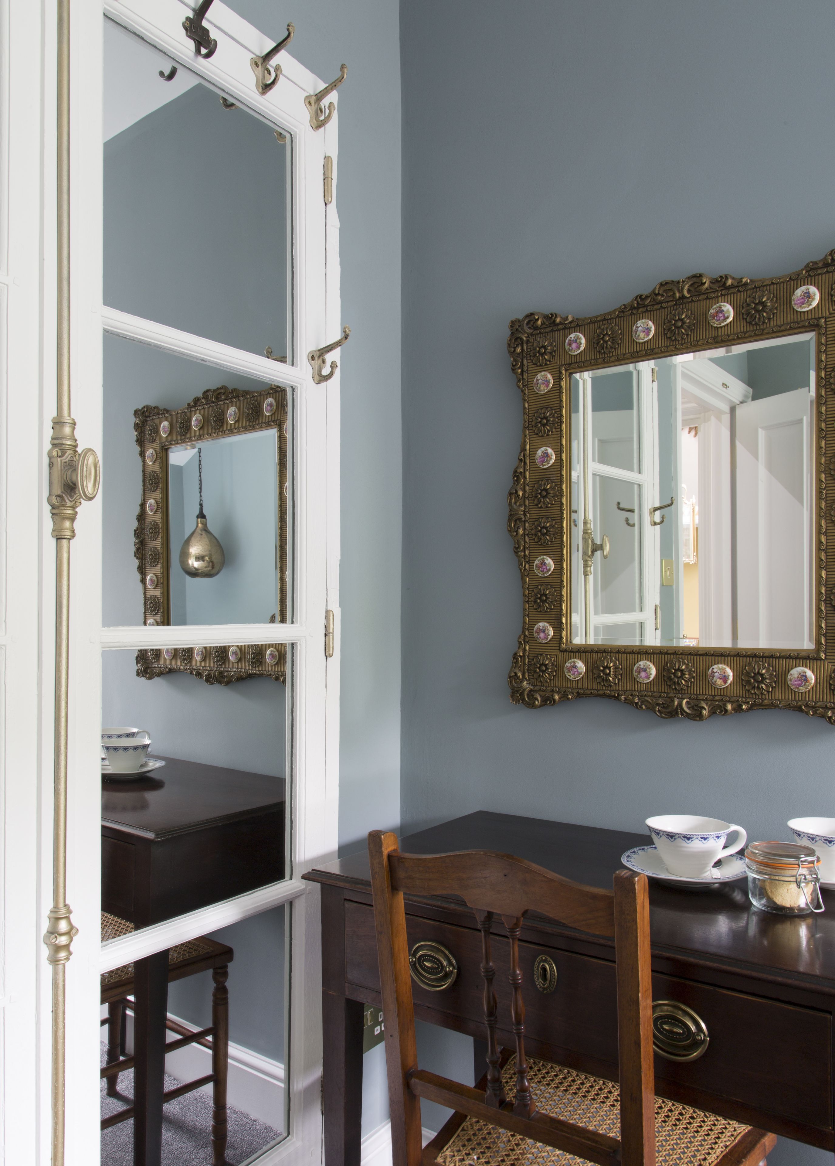 Una habitación con un aparador de madera oscura, una silla y una mesa con una tetera y tazas.