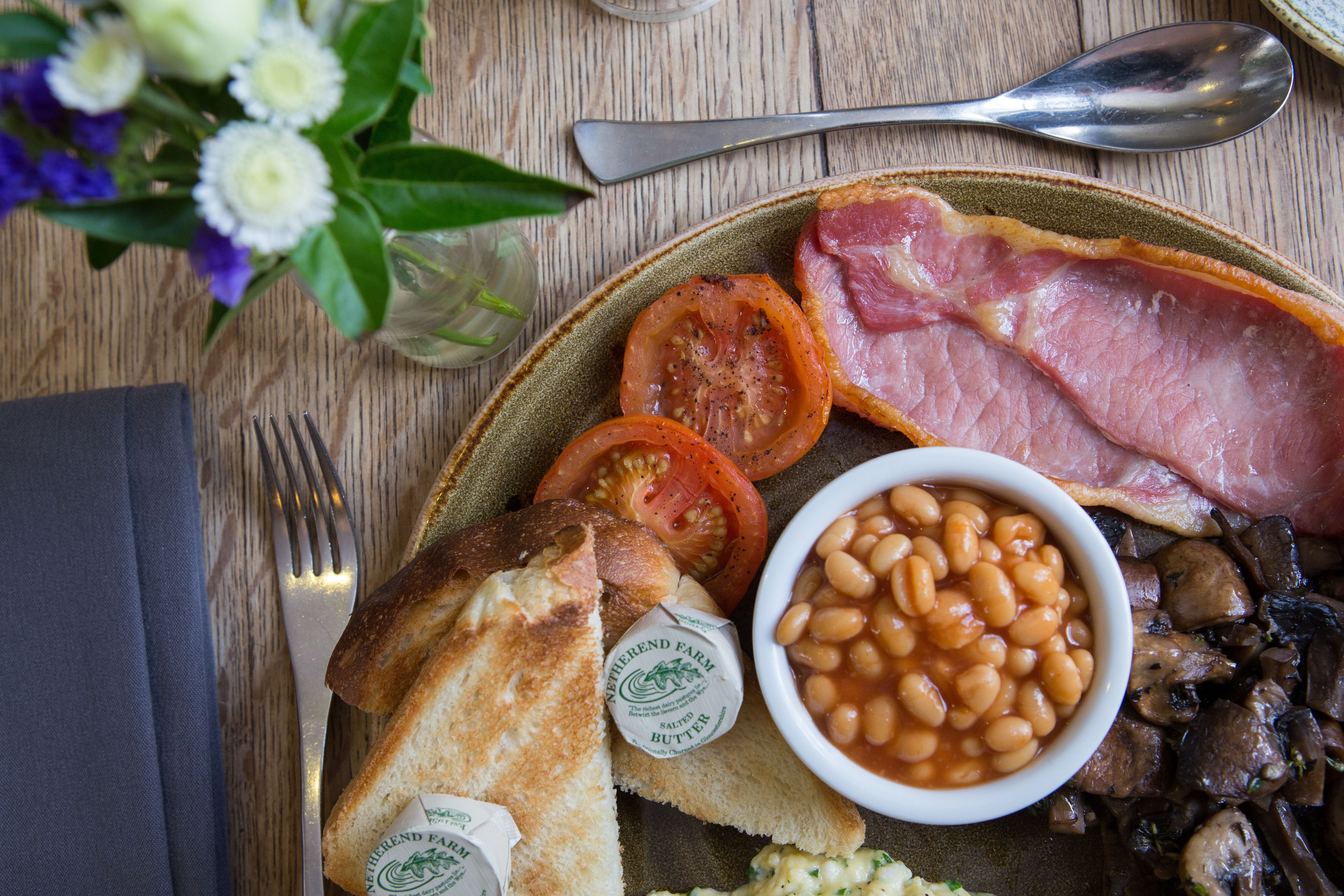 A breakfast plate with toast, tomatoes, beans, mushrooms, and ham.