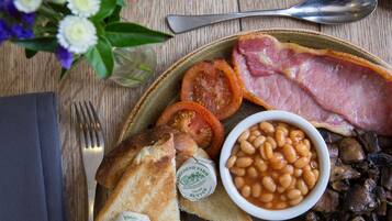 A breakfast plate with toast, tomatoes, beans, mushrooms, and ham.