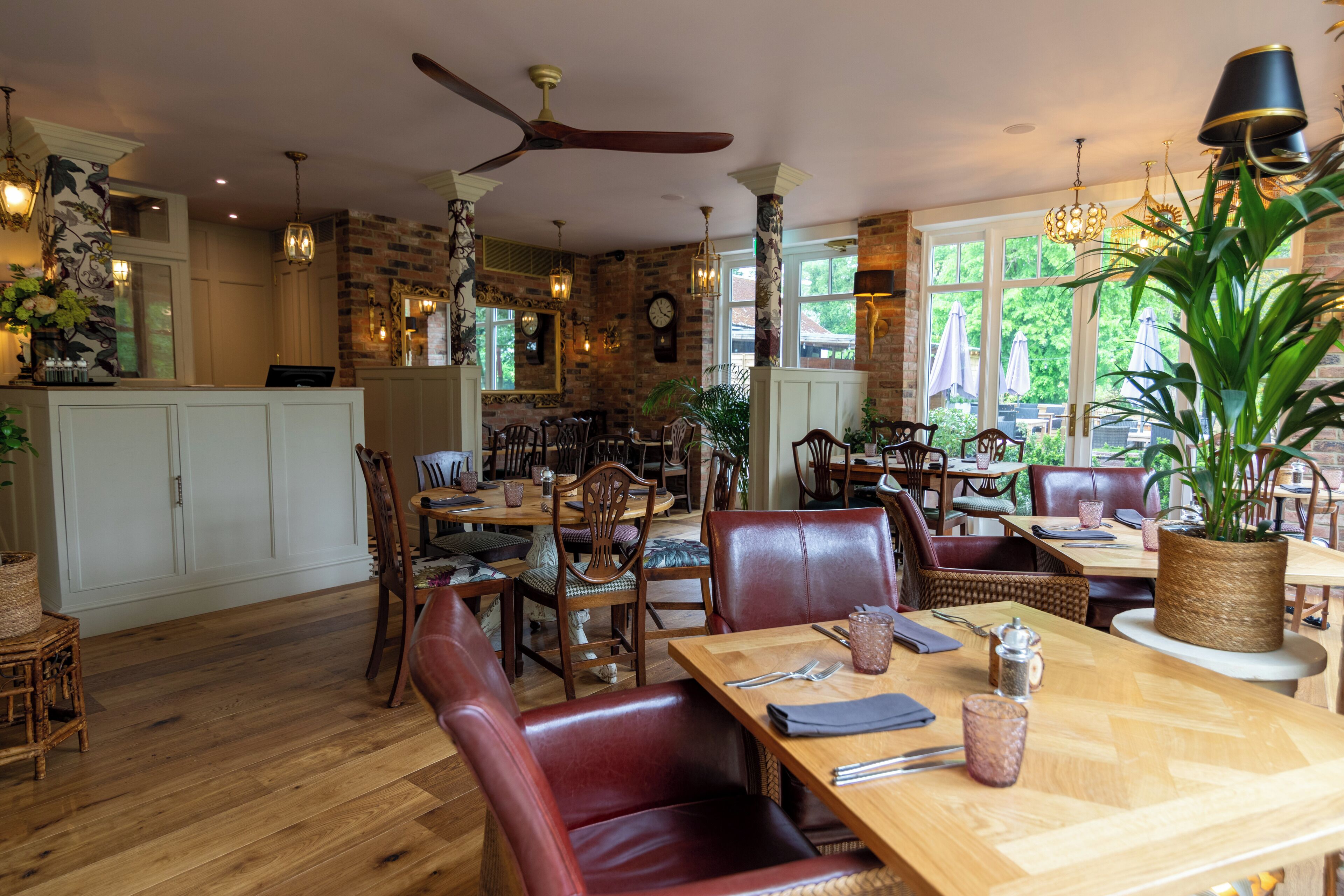 Een restaurant met houten vloeren, lederen zitplaatsen en een grote plant als middelpunt.