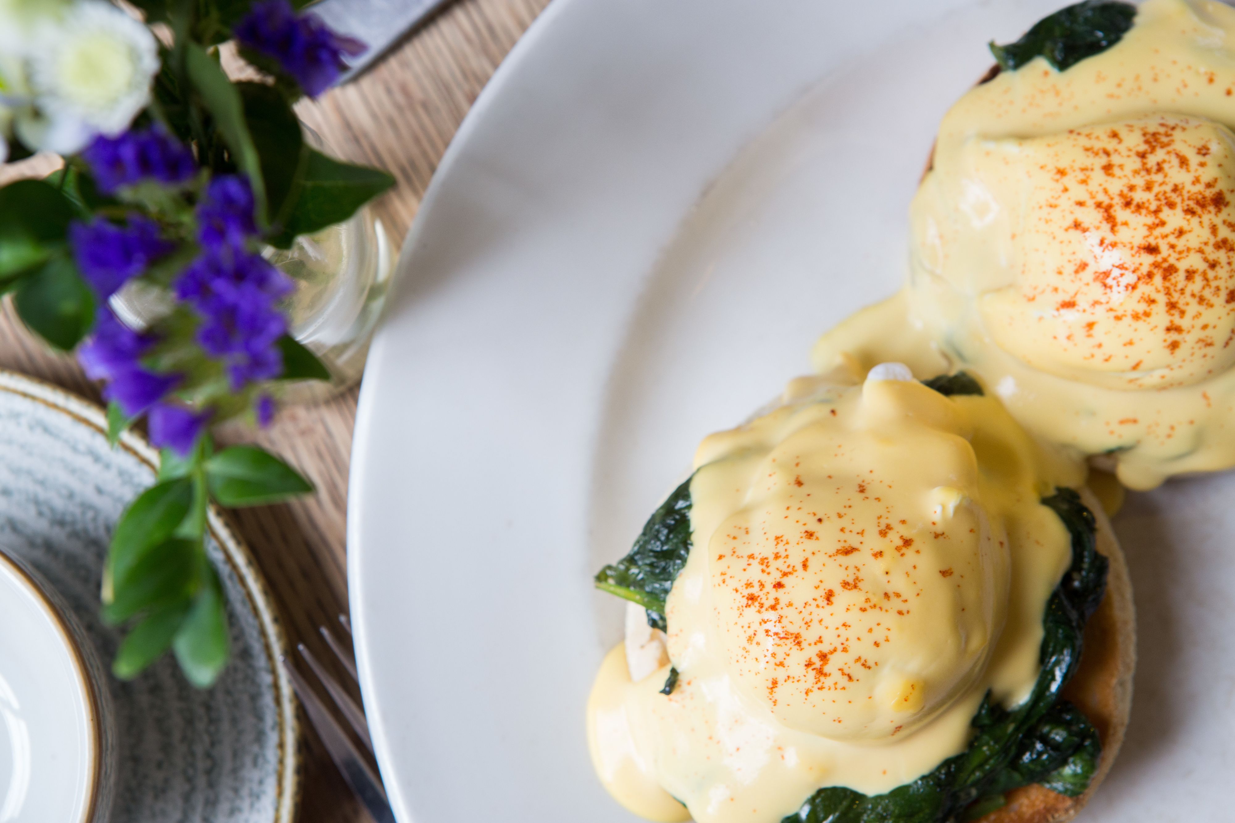 A plate of eggs benedict with hollandaise sauce and a sprinkle of paprika.