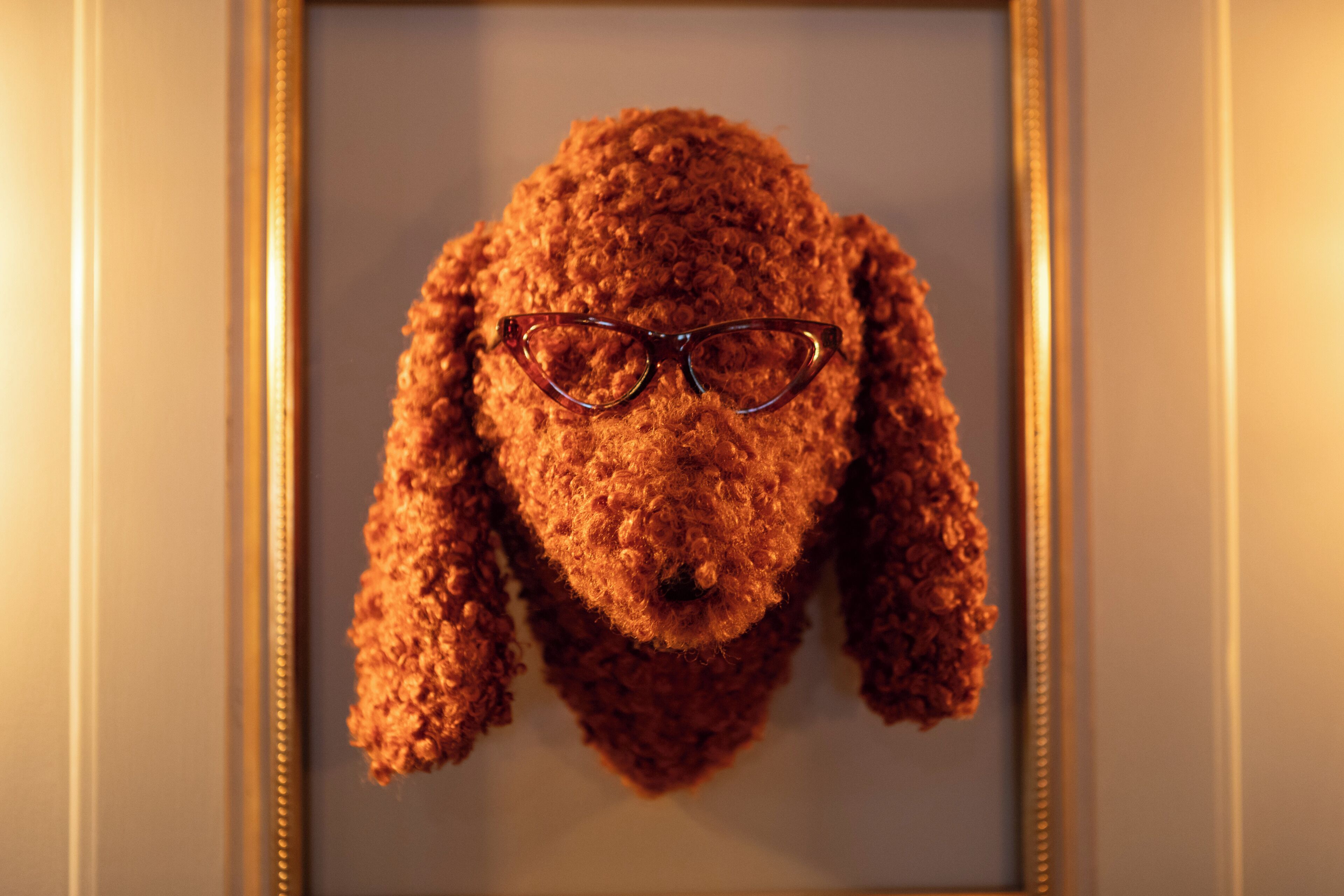 A framed sculpture of a dog wearing glasses.