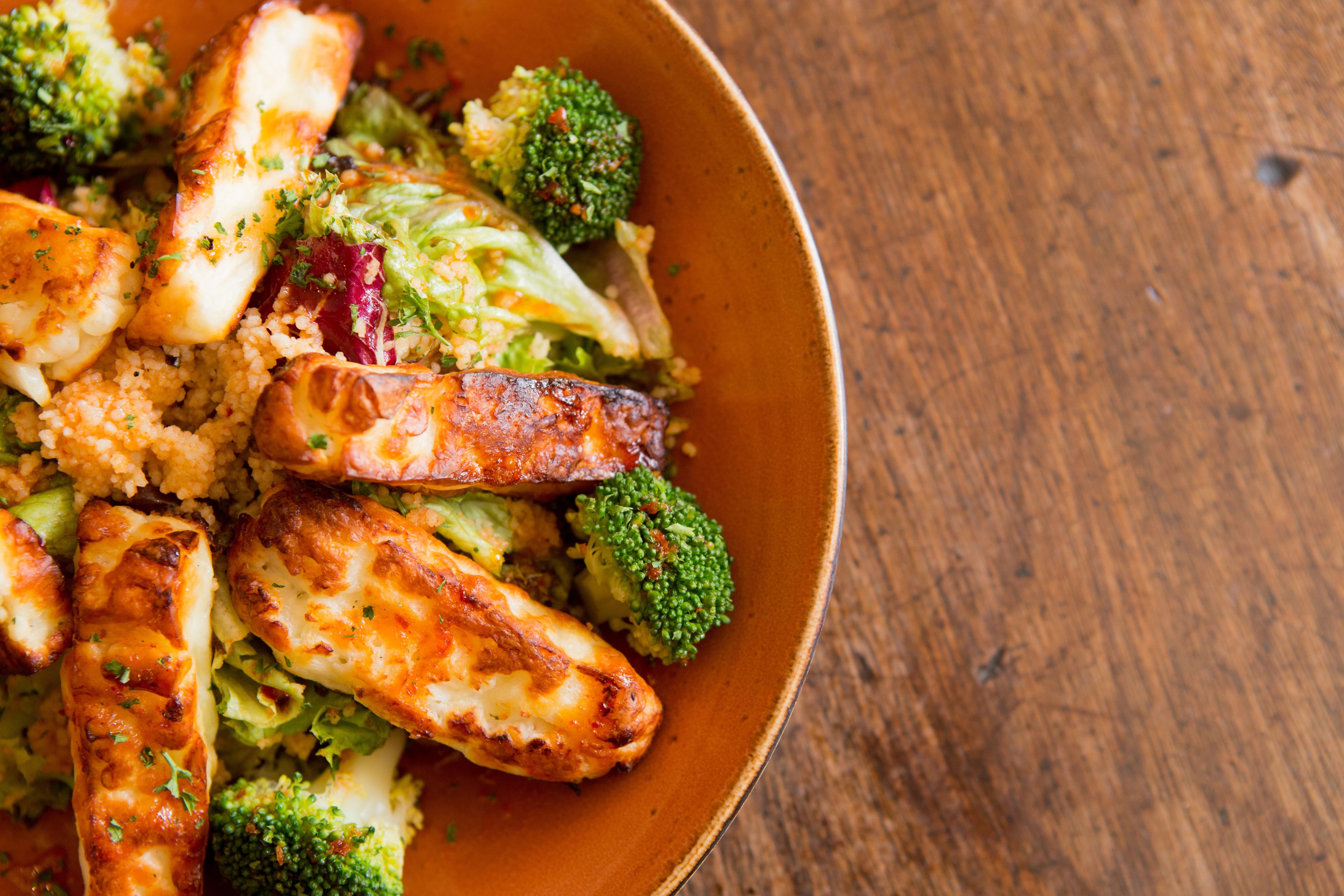 A bowl of food with grilled chicken, broccoli, and red cabbage.