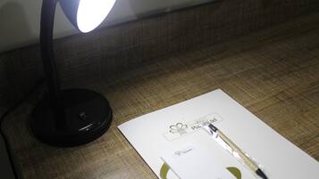 Een bureau met een lamp, een pen en een wit notitieboekje.