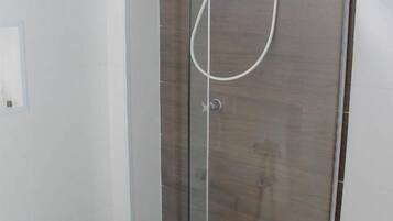 A glass-enclosed shower with a handheld showerhead and a wall-mounted faucet.