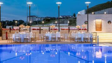 Een buitenzwembad, ligstoelen bij het zwembad