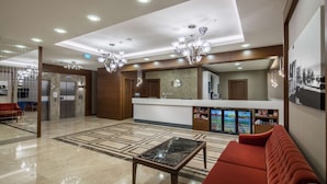 A hotel lobby with a reception desk, a red sofa, a marble coffee table, and a chandelier. - Hampton by Hilton Canakkale Gallipoli (Gallipoli)