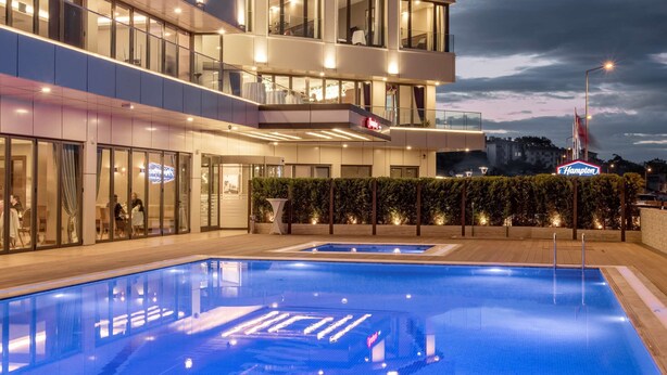 A modern hotel with a swimming pool, multiple balconies, and a well-lit facade. - Hampton by Hilton Canakkale Gallipoli (Gallipoli)