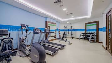 Un gimnasio con cintas de correr, elípticas y equipo de levantamiento de pesas.