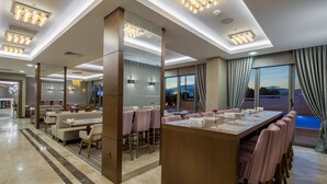 A modern hotel dining area with a long communal table, several booths, and a bar area. - Hampton by Hilton Canakkale Gallipoli (Gallipoli)