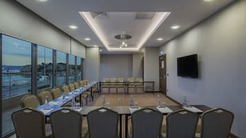A conference room with a long table, chairs, and a TV screen.