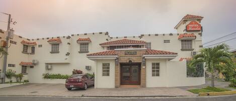 A hotel with a tiled roof, a central entrance with a door, and a sign indicating it is a hotel.