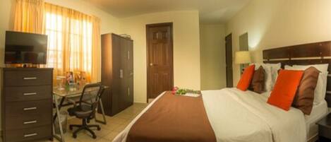 Habitación de hotel con una cama, un escritorio con silla, televisión y armario.