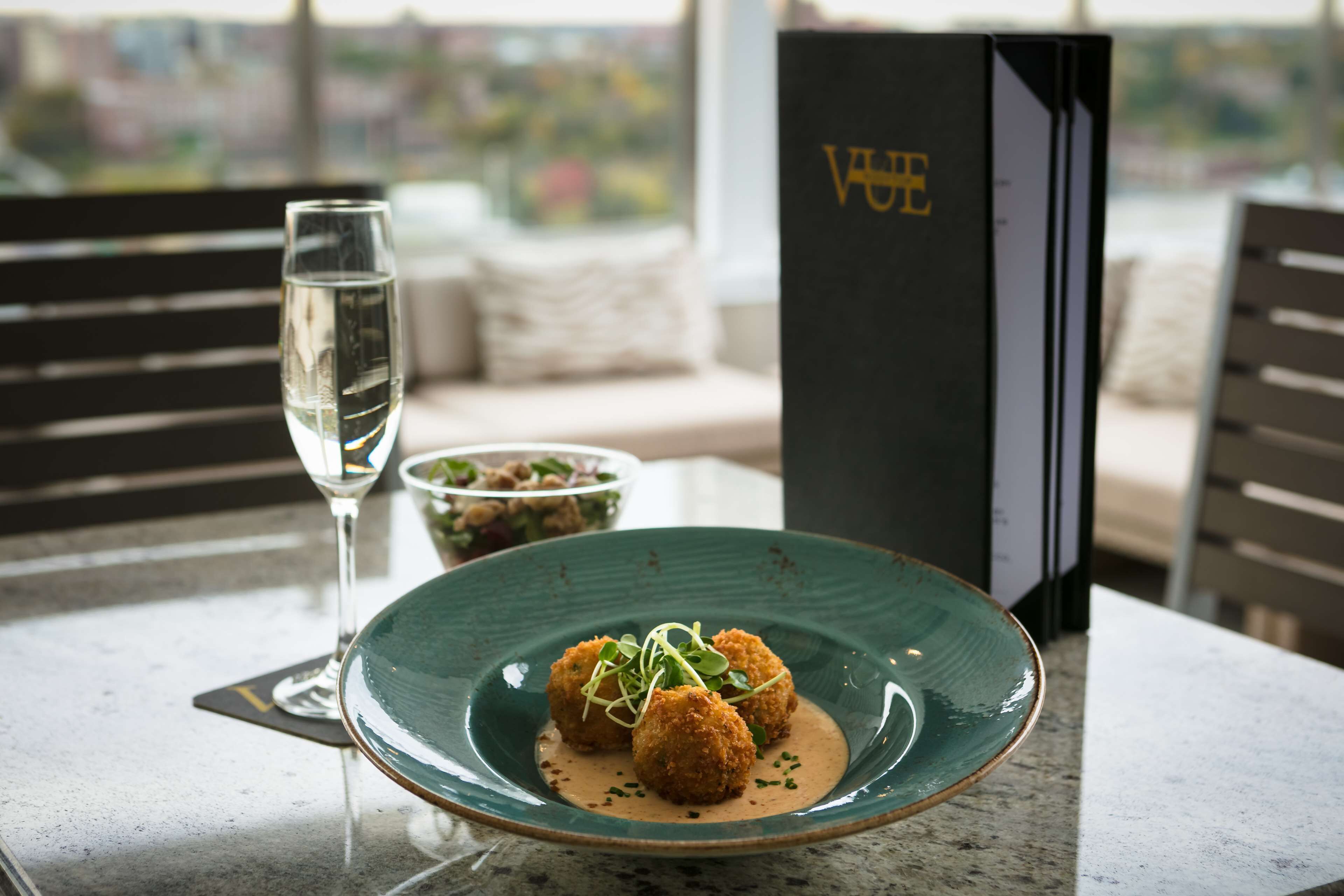 A dining table with a plate of food, a glass of water, and a menu.
