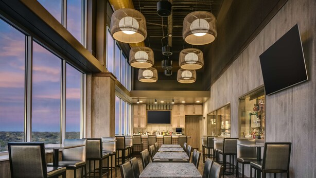 Un restaurante amplio con techos altos, ventanas grandes y una zona de bar.