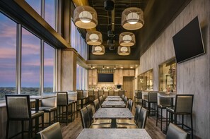 Un restaurante amplio con techos altos, ventanas grandes y una zona de bar.