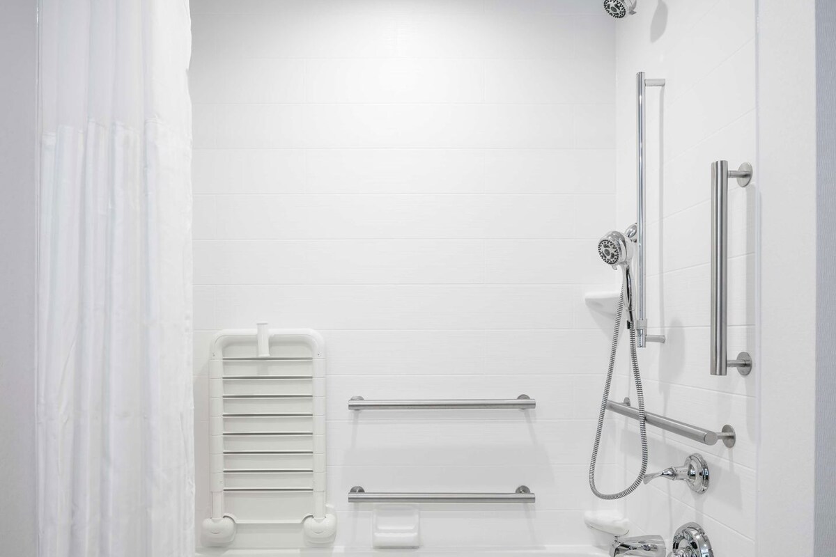 Un baño moderno con bañera, ducha y barras de apoyo.