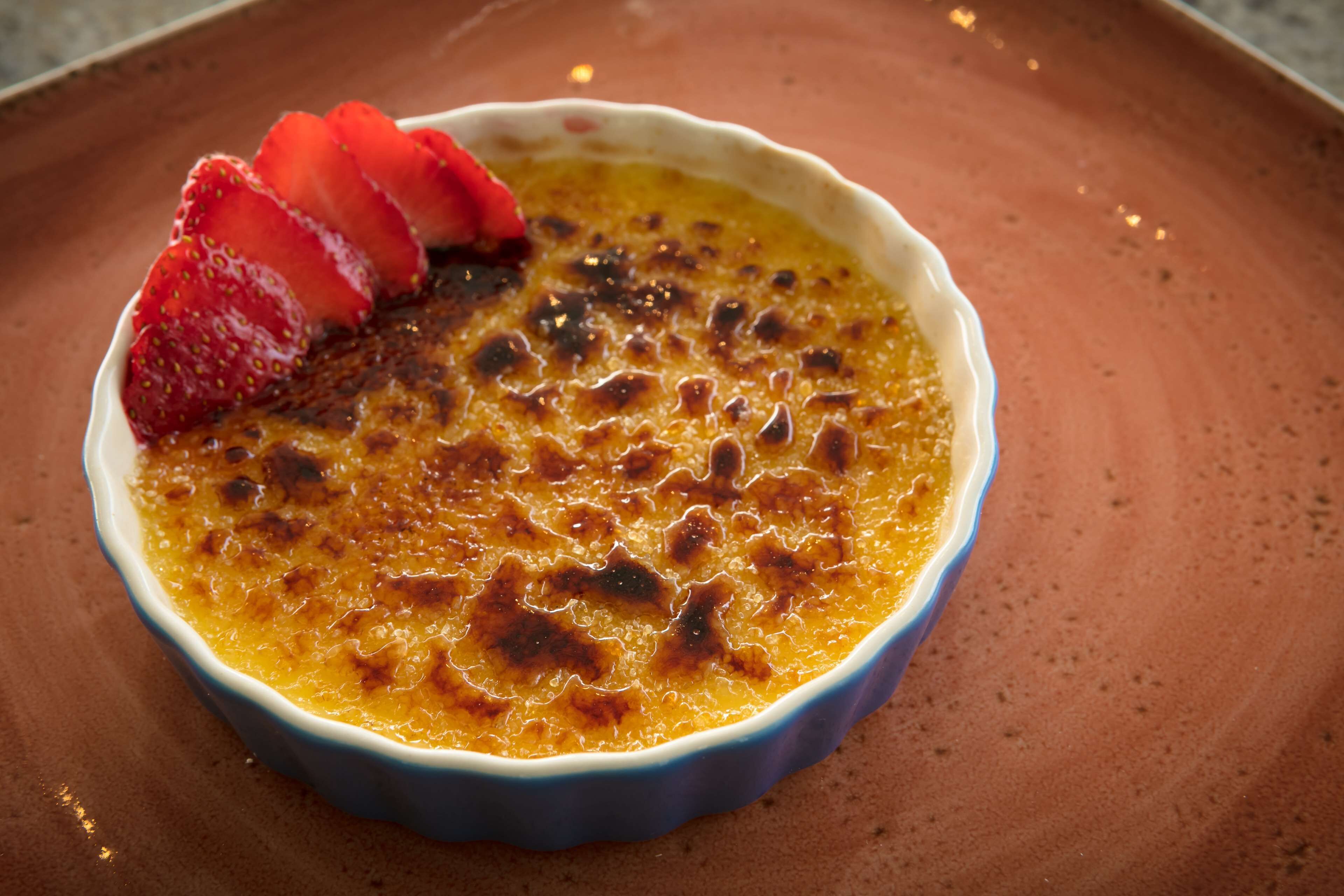 A dessert in a blue ramekin on a terracotta plate.