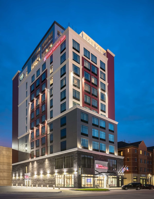 Un hôtel à plusieurs étages au design moderne, reconnaissable à son grand panneau indiquant « Hilton Garden Inn ».