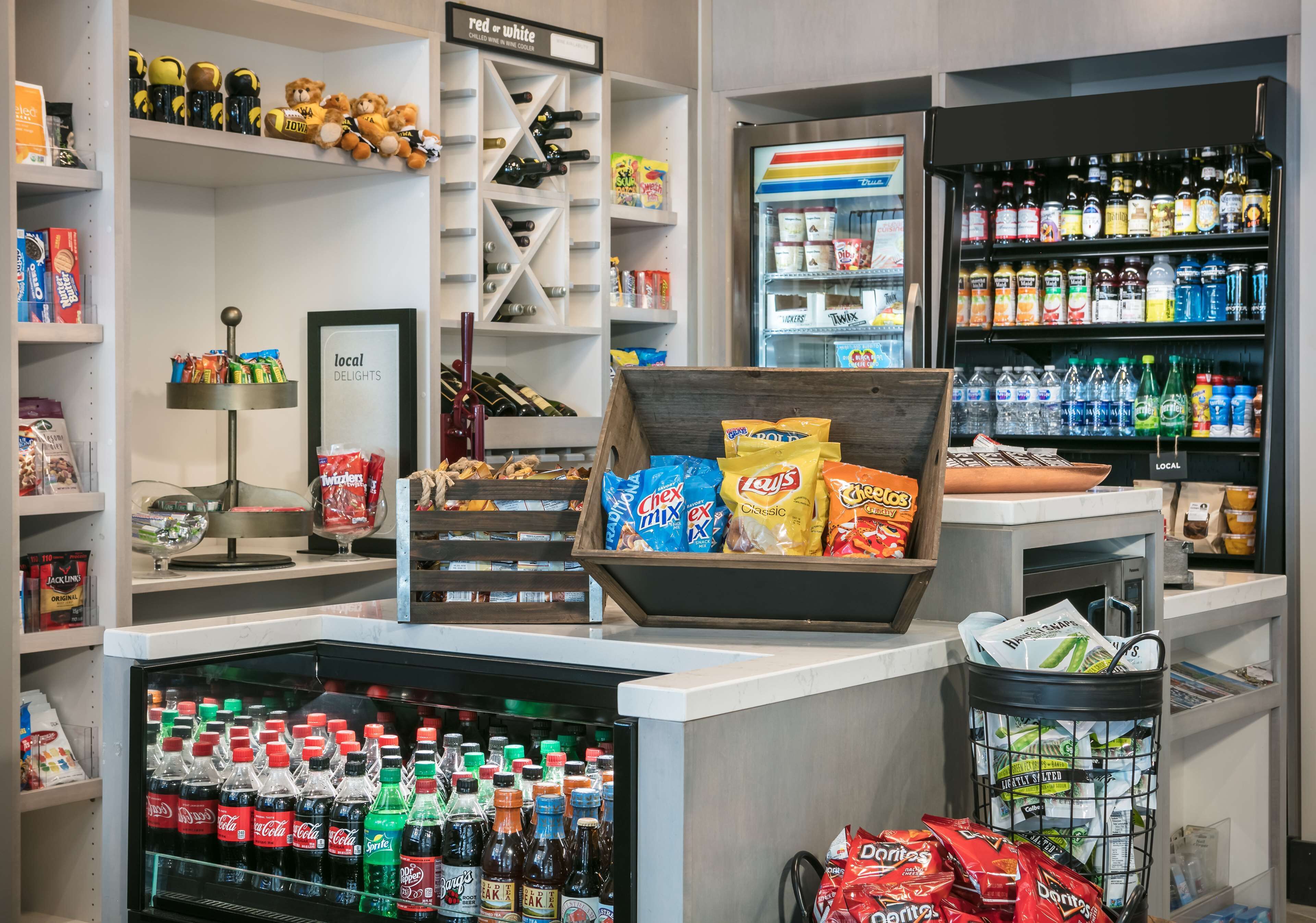 A store with shelves stocked with snacks, a refrigerator with beverages, and a display of bottled water.