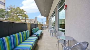 An outdoor patio with striped seating, metal tables, and chairs.