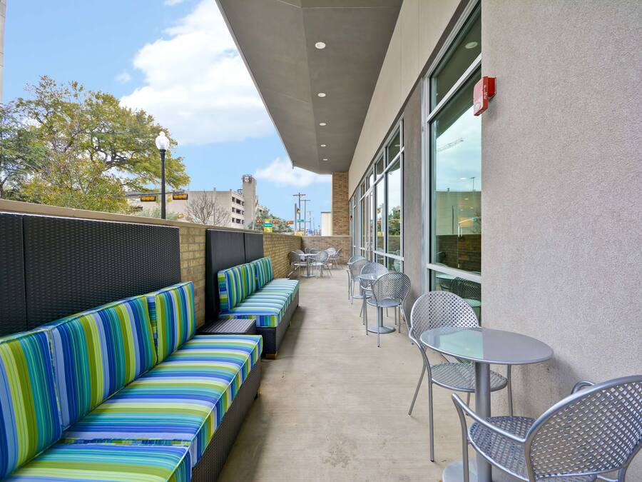 An outdoor patio with striped seating, metal tables, and chairs.