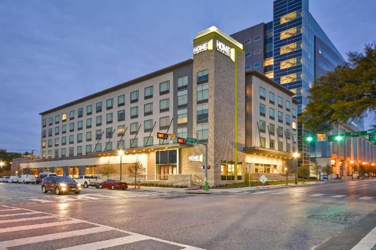 Un hotel con un letrero grande que dice 'HOME', un estacionamiento y la intersección de dos calles.