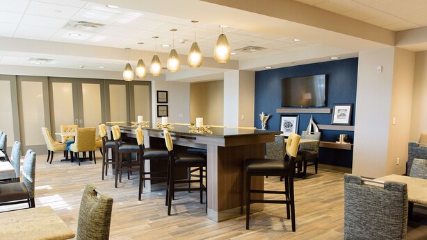 A modern hotel lobby with a bar area, seating arrangements, and a television screen on the wall. - Hampton Inn Superior Duluth (Superior)
