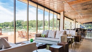 Amplio espacio interior con un ventanal grande que da a un paisaje natural. Hay un sofá y una mesa de centro con un libro encima.