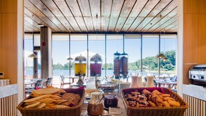 Un bufé de desayuno con diversos alimentos y bebidas, vistas al exterior y un diseño de interiores moderno.