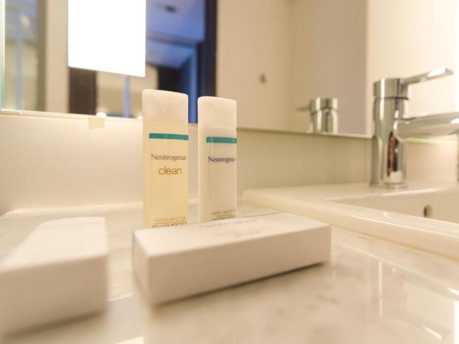 Une salle de bain avec un lavabo blanc, deux flacons de lotion hydratante Neutrogena Clean Skin et un porte-savon blanc.