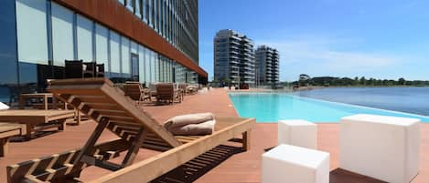 Una piscina al aire libre, sillones reclinables de piscina