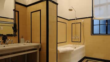 Casa de banho com banheira, lavatório, espelho e chuveiro.