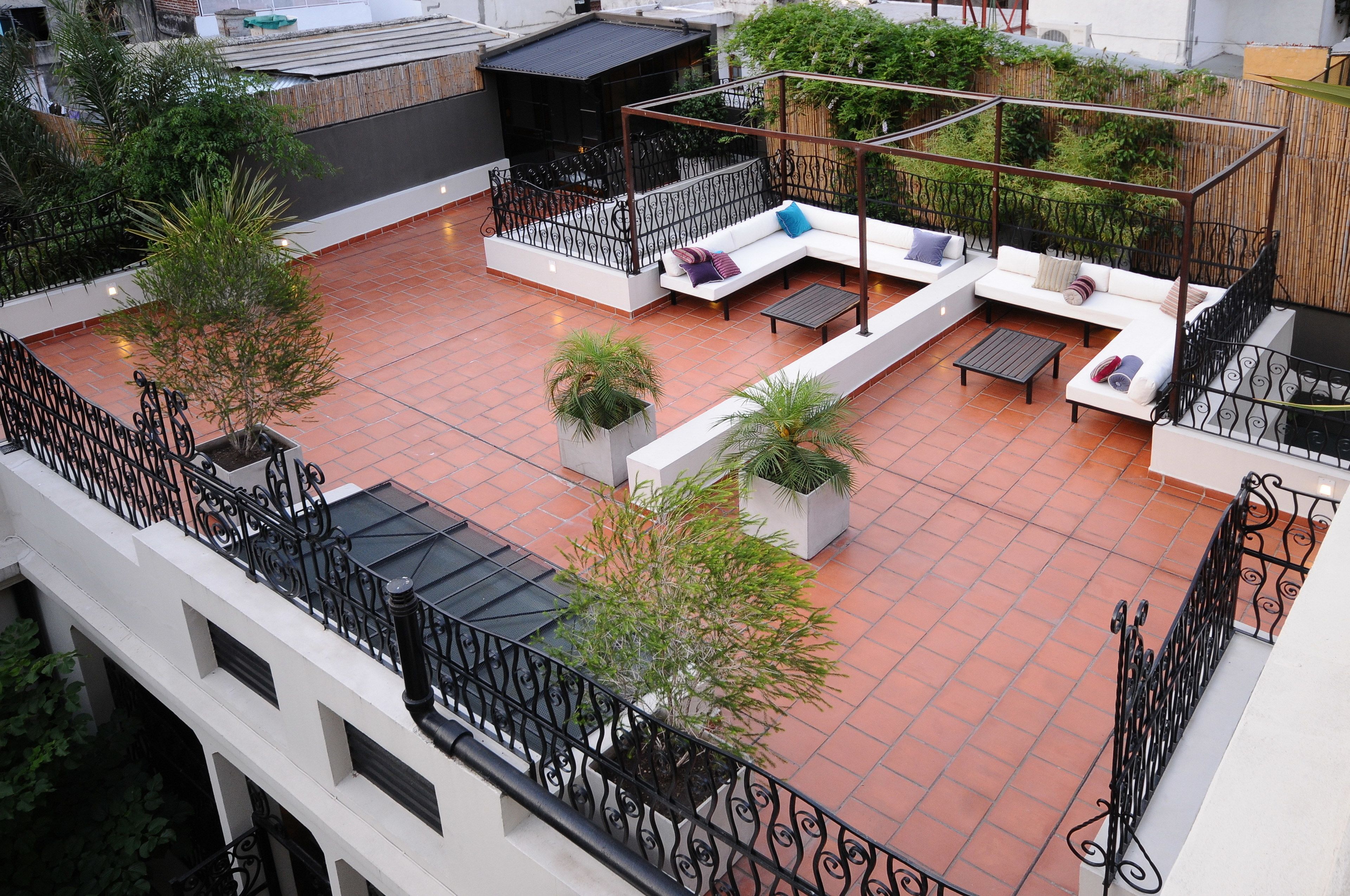 A rooftop patio with outdoor seating, potted plants, and a view of the cityscape.