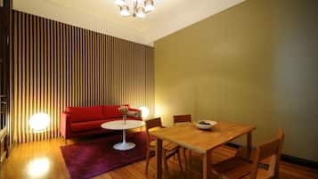 A modern living room with a red sofa, a round coffee table, and a wooden dining table with chairs.