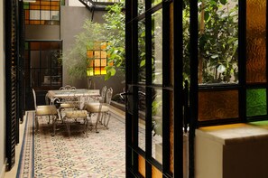 Un interior japonés tradicional con suelo de esteras de tatami, una mesa baja con sillas y vistas a un exuberante jardín a través de un panel shoji.