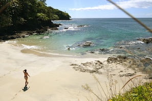 A beach with clear turquoise water, a sandy shore, and a person walking. - Cebaco Sunrise Lodge (Isla Cebaco)