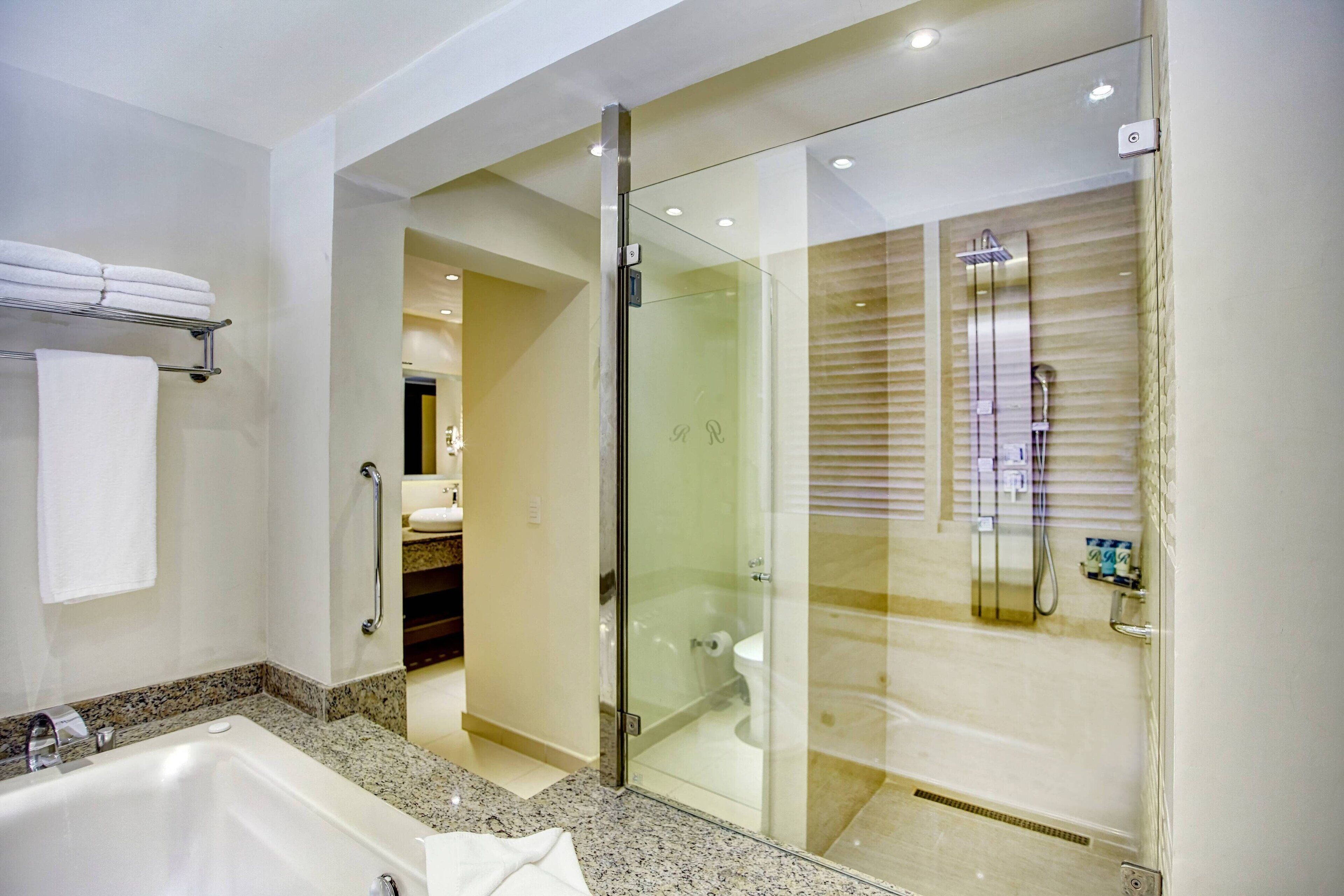 Une salle de bain moderne dotée d’une douche à parois de verre, d’une grande baignoire et d’un comptoir en granit.