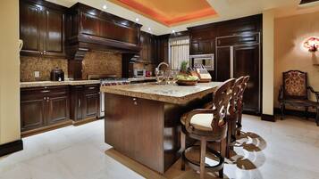 A spacious kitchen with dark wood cabinets, granite countertops, and a central island with bar stools.