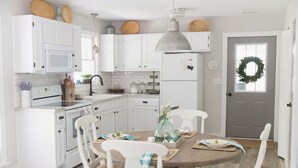 A kitchen with white cabinets, a dining table with chairs, and a refrigerator. - Mountain Air Cabin near Franklin, Cashiers and Highlands, North Carolina (Franklin)