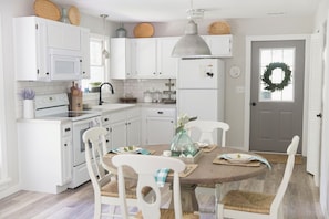 A kitchen with white cabinets, a dining table with chairs, and a refrigerator.