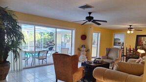A living room with a sofa, armchair, ceiling fan, and a view to an outdoor patio with a pool. - #1 SIESTA KEY Beach Glass House w/supplies
 PRICE Breaks w/ 3 payments ! (Siesta Key)